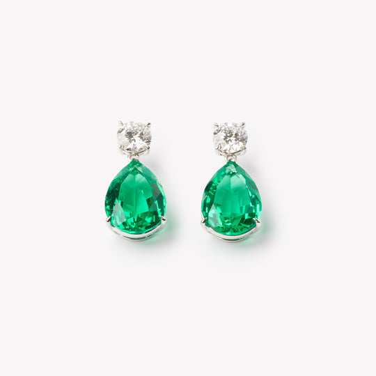 18k gold lab grown diamond and emerald earrings. Round brilliant and pear cut with tiger claw setting.