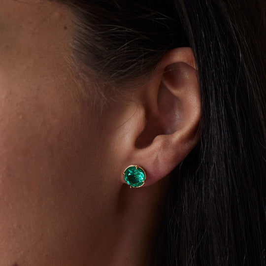 18k gold lab grown emerald studs. Round brilliant cut with tiger claw setting. On model.