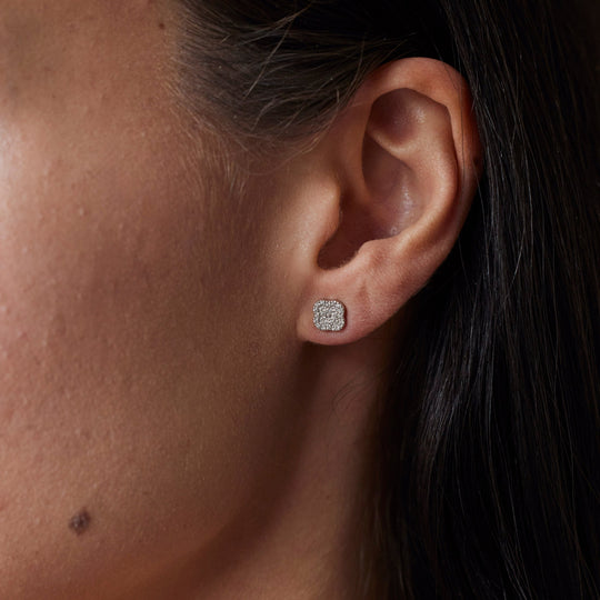 18k gold lab grown diamond studs. rounded square shape with round cut diamonds. On Model.