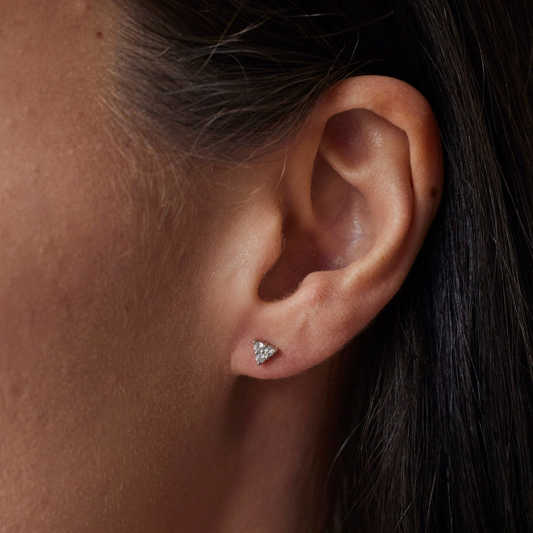 18k gold lab grown diamond studs. round brilliant diamonds in triangular shape. On Model.
