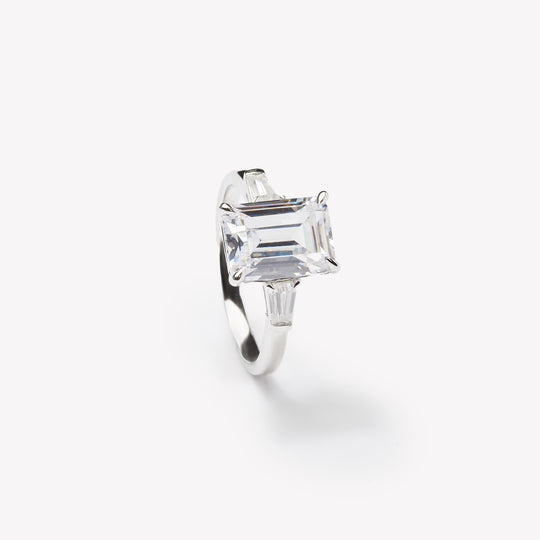 Emerald cut three-stone engagement ring by IRALIS – Zurich-designed fine jewelry with DEF color and VS1–VS2 clarity.