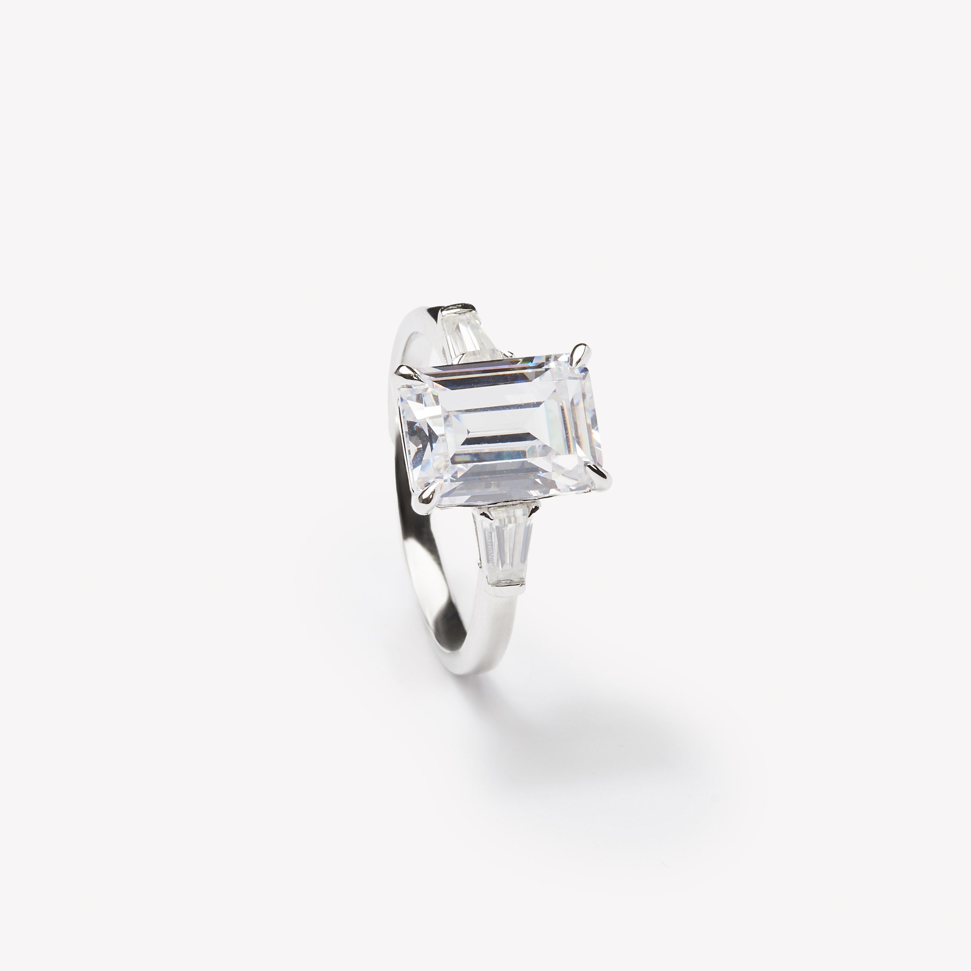 Emerald cut three-stone engagement ring by IRALIS – Zurich-designed fine jewelry with DEF color and VS1–VS2 clarity.