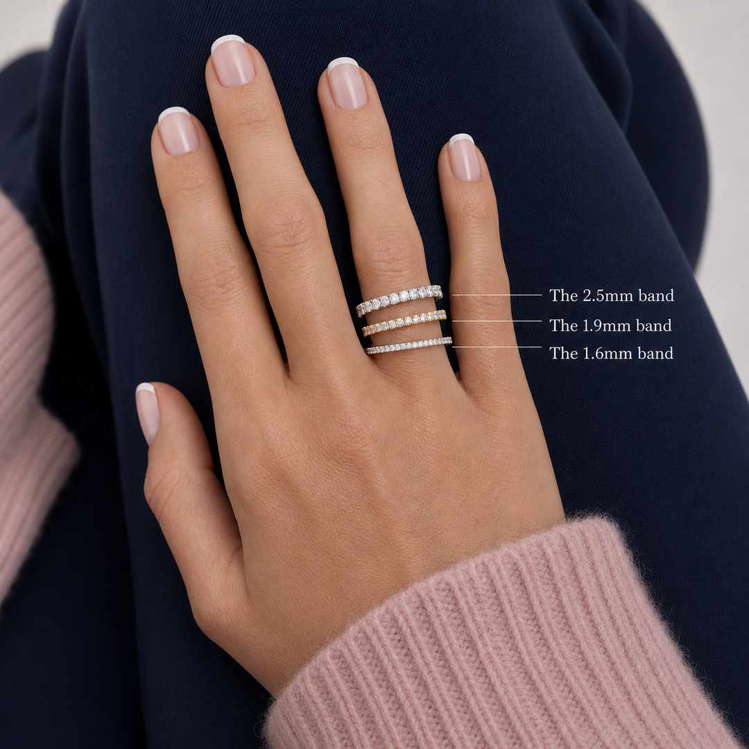 A close-up of a hand wearing three eternity  rings with different band widths labeled as 1.6mm, 1.9mm, 2.5mm