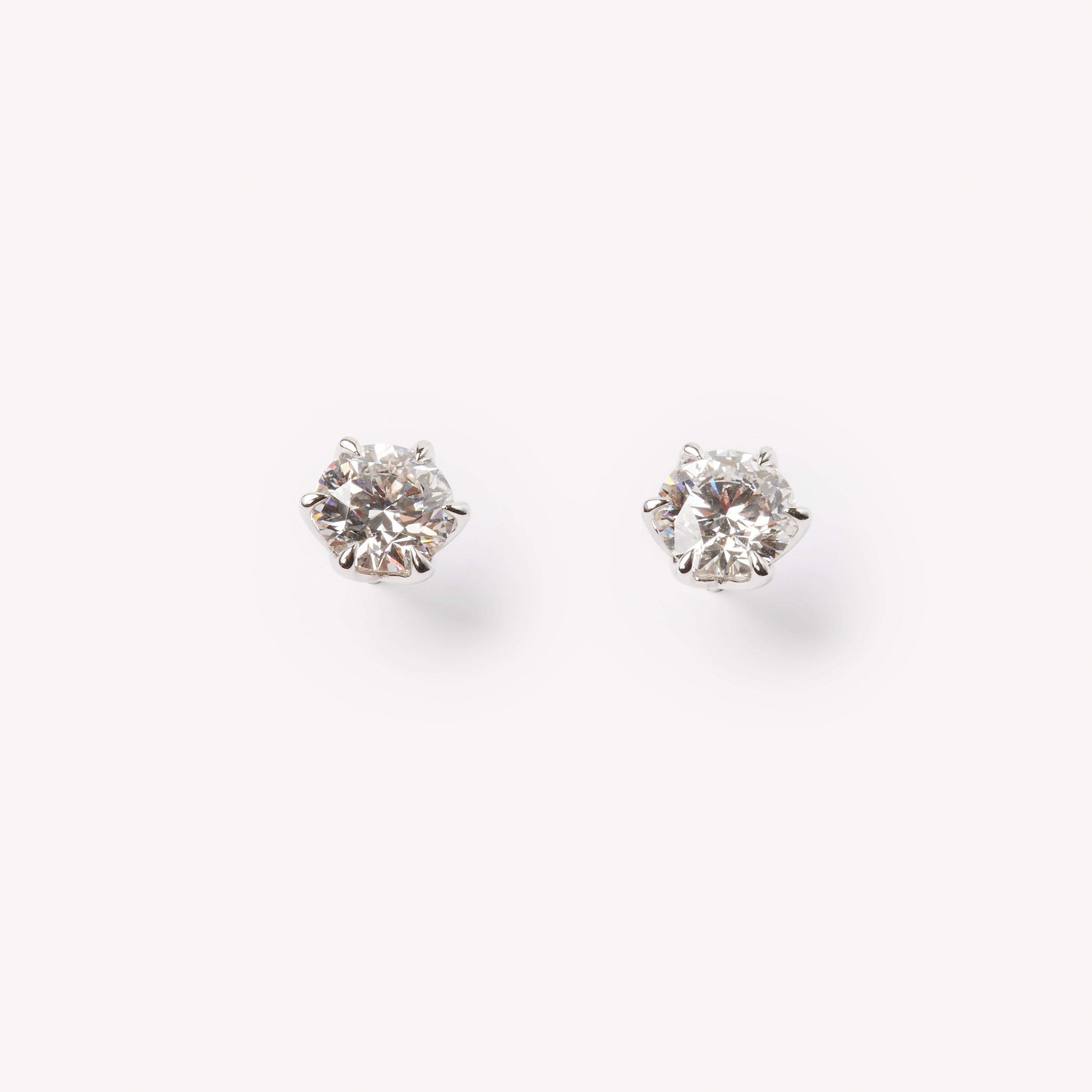 Elegant round brilliant cut diamond stud earrings in 18k white gold prong settings, minimalist luxury style.